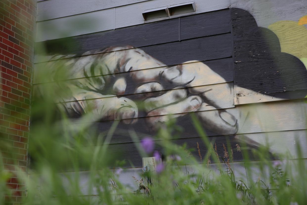 A mural painted on the side of a boarded up apartment complex in Eagle Butte depicts an infant holding the hand of an elder.