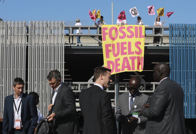 Activistas medioambientales de Extinction Rebellion sostienen una pancarta que dice "Combustibles fósiles-Muerte) mientras protestan en la Semana de la Energía de África, el 20 de octubre de 2022 en Ciudad del Cabo, Sudáfrica.