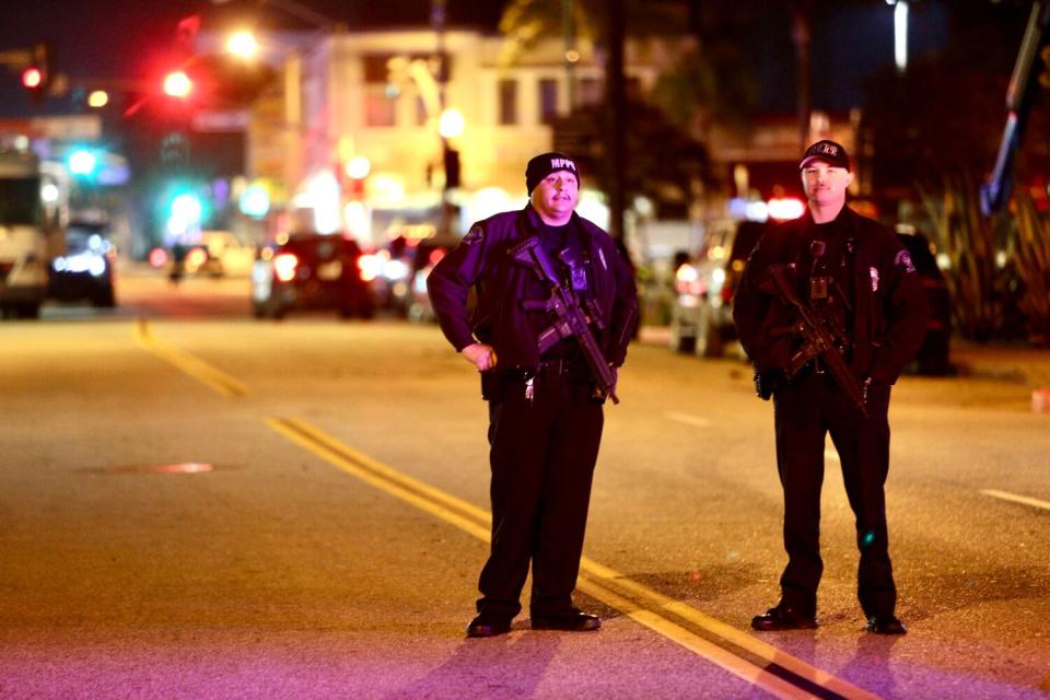 Two police officers stand in a middle of a road in city environment, at night.