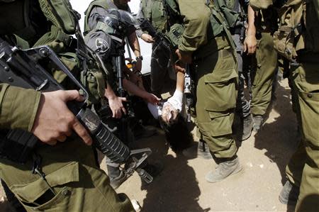 Israeli soldiers carry French diplomat Marion Castaing after removing her from her truck containing emergency aid, in the West Bank herding community of Khirbet al-Makhul, in the Jordan Valley September 20, 2013. REUTERS/Abed Omar Qusini