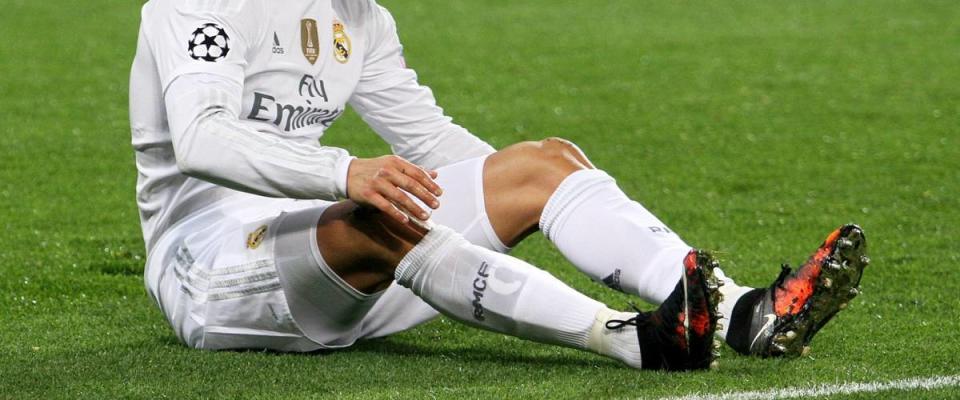 Soccer player Cristiano Ronaldo leaning over his cleats on the soccer pitch