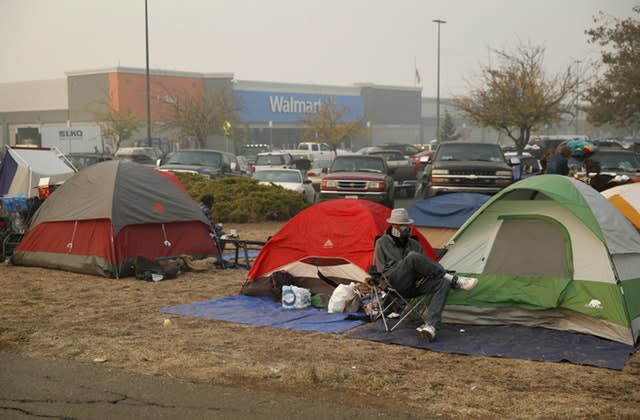 People sit by their tents at a makeshift encampment outside a Walmart store for people displaced by the Camp Fire