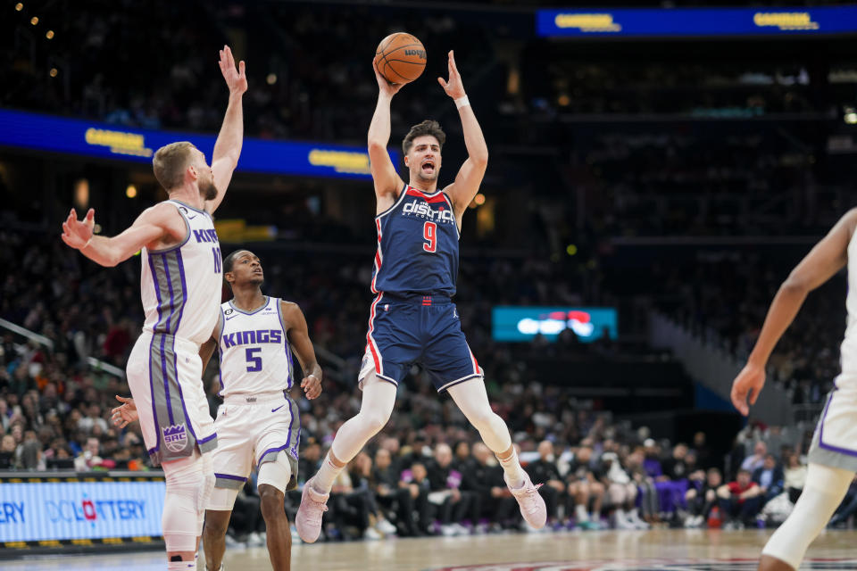 Washington Wizards forward Deni Avdija (9) passes the ball as Sacramento Kings forward Domantas Sabonis (10) and guard De'Aaron Fox (5) defend during the first half of an NBA basketball game Saturday, March 18, 2023, in Washington. (AP Photo/Jess Rapfogel)