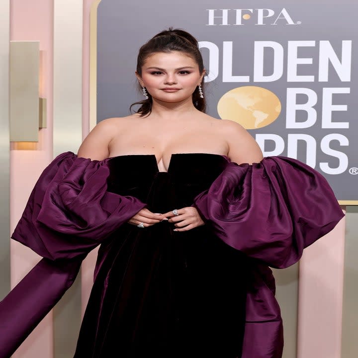 Selena poses on the Golden Globes red carpet wearing a velvet off-shoulder dress with balloon sleeves