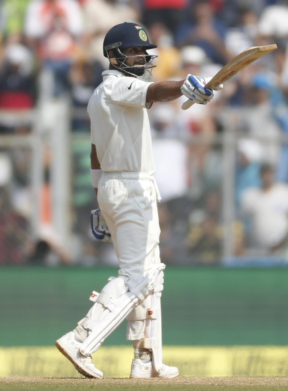 Indian cricket captain Virat Kohli raises his bat after scoring 50 runs on the third day of the fourth cricket test match between India and England in Mumbai, India, Saturday, Dec. 10, 2016. (AP Photo/Rafiq Maqbool)