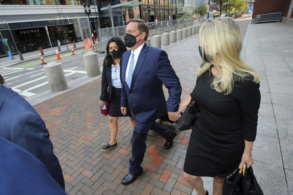 John Wilson, center, holds his wife's hand, right, as he leaves the John Joseph Moakley Federal Courthouse after the first day of his trial in the college admissions scandal, Monday, Sept. 13, 2021, in Boston. (AP Photo/Stew Milne)