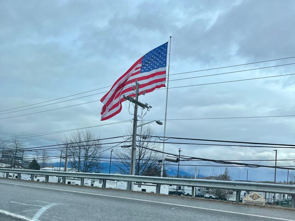 car driving past an american flag on the side of a highway near Seattle Washington