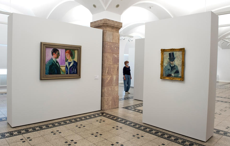 A visitor attends one of the exhibition rooms of the permanent exhibition behind the paintings 'Kaete and Hugo Perls‘ (1913) by Edvard Munch, left and 'Self-portrait with mask‘ (1910) by Paul Wilhelm, right, in the Chemnitz Art Collections (Kunstsammlungen) in Chemnitz, eastern Germany, Monday, May 4, 2020. The German state Saxony has reopened museums and exhibitions under certain conditions after the coronavirus lockdown. (AP Photo/Jens Meyer)