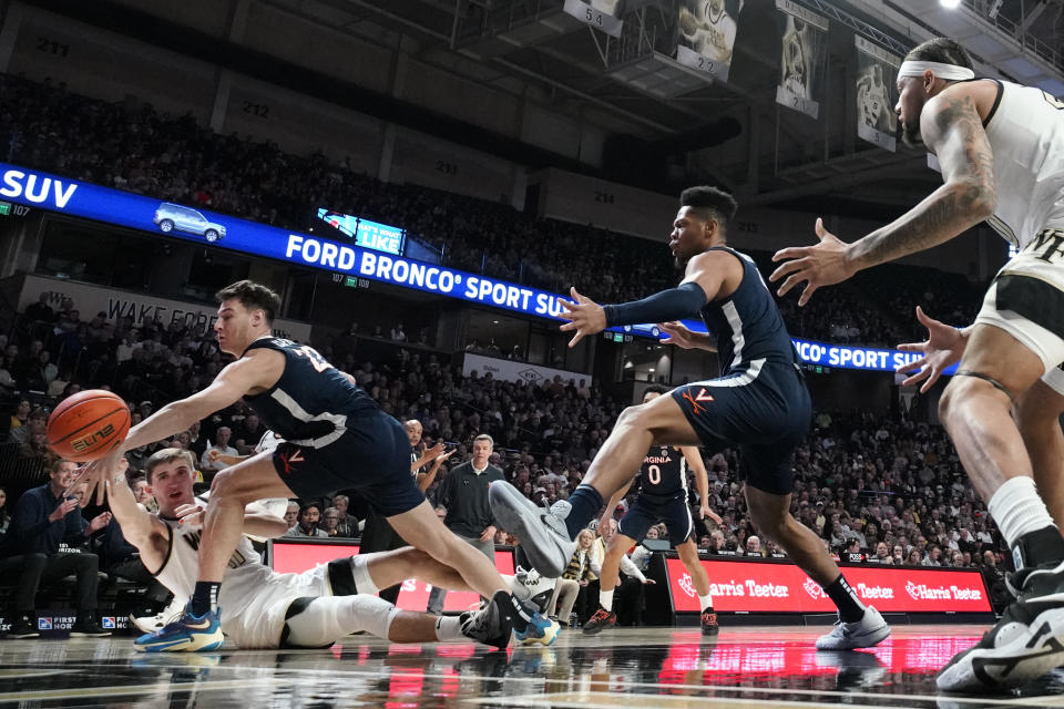 Wake Forest forward Andrew Carr (11) tries to pass the ball around Virginia center Francisco Caffaro (22) and Virginia forward Jayden Gardner (1) during the first half of an NCAA college basketball game in Winston-Salem, N.C., Saturday, Jan. 21, 2023. (AP Photo/Chuck Burton)