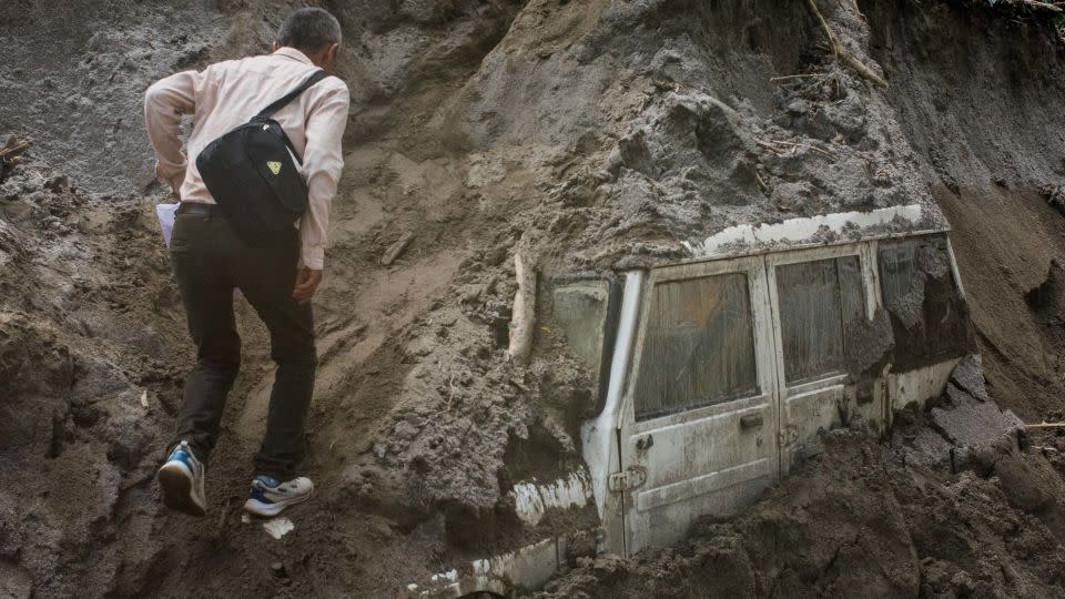 A man walks next to a vehicle buried in mud due to floods, in Teesta Bazaar, Kalimpong District, West Bengal, India October 7, 2023.  - Birat Rai/Reuters