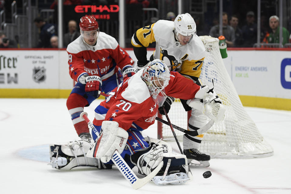 Washington Capitals goaltender Braden Holtby (70) and Pittsburgh Penguins center Evgeni Malkin (71) battle for the puck during the first period of an NHL hockey game, Sunday, Feb. 23, 2020, in Washington. Also seen is Capitals defenseman Dmitry Orlov (9). (AP Photo/Nick Wass)