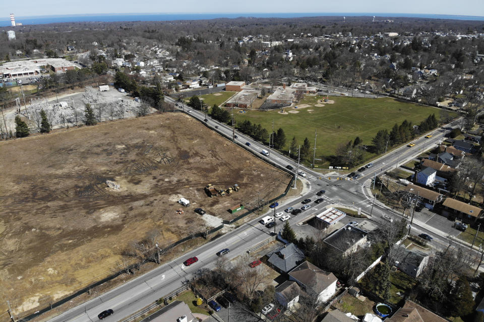 A plot of land that is being developed into multifamily housing, left, is seen in East Northport, N.Y., Thursday, March 16, 2023. Some elected officials from Long Island claim their suburban way of life is threatened by New York Gov. Kathy Hochul's plan to spur more housing construction. They claim it would swamp the area with new apartment buildings and turn it into a "sixth borough" of the city. (AP Photo/Seth Wenig)