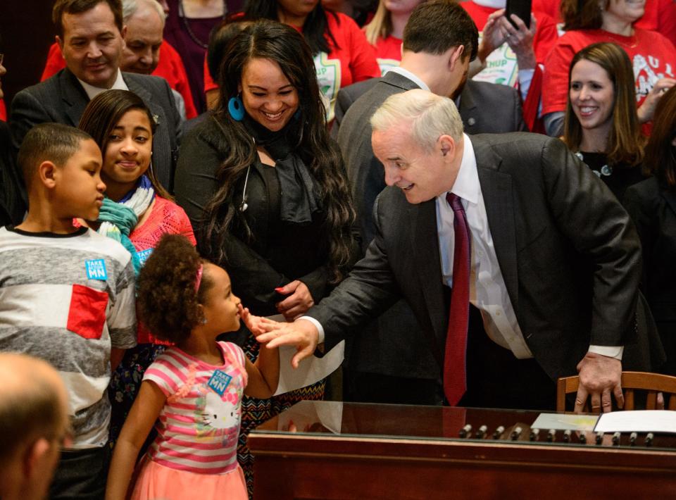 Governor Mark Dayton high-fives Ashia Rhodes after signing the minimum wage bill into law at a public bill signing ceremony Monday, April 14, 2014 at the Minnesota State Capitol Rotunda in St. Paul. Minnesota goes from having one of the nation's lowest minimums to among the highest. With federal wage legislation stuck in Congress, states are rushing to fill the void. (AP Photo/The Star Tribune, Glen Stubbe) MANDATORY CREDIT; ST. PAUL PIONEER PRESS OUT; MAGS OUT; TWIN CITIES TV OUT