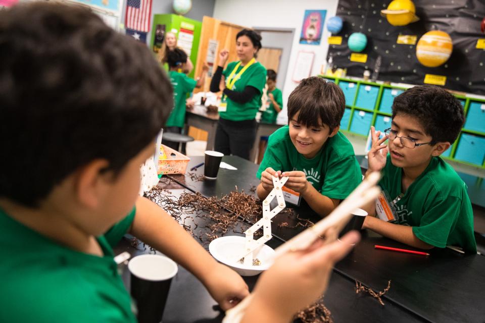 Clinton Bonilla, center, uses a grabbing device to pick up objects during a game at Camp Invention at Windsor Park Elementary School on Thursday, June 16, 2022.