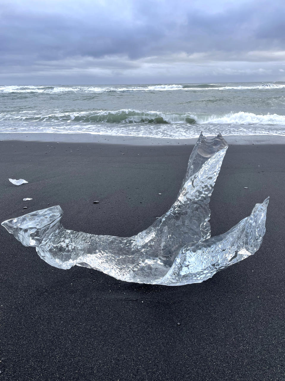 This Nov. 18, 2023 image provided by Beth Harpaz shows a large chunk of ice melting into a fanciful bird-like shape on Diamond Beach on Iceland's South Coast. The beach is dotted with glistening ice chunks that break off from a glacier, float into the Jokulsarlon glacier lagoon and onto the volcanic black sand. (Beth Harpaz via AP)