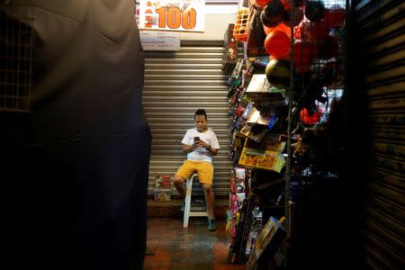 A vendor uses a mobile phone to surf internet outside a toy shop in Paranaque, Metro Manila, Philippines July 7, 2016. Picture taken July 7, 2016. REUTERS/Erik De Castro