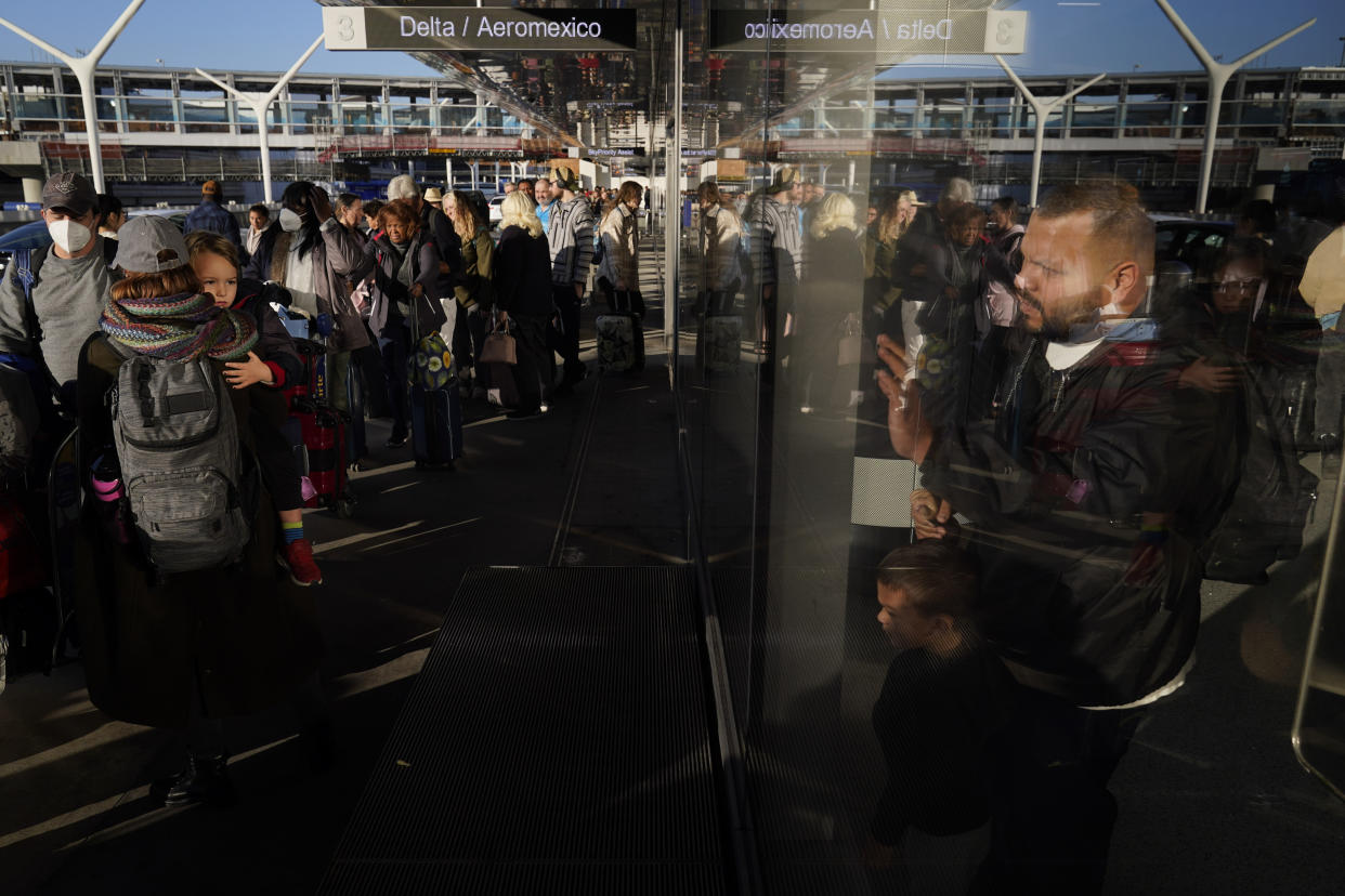 People wait in line to check in at Los Angeles International Airport in Los Angeles, Monday, Dec. 19, 2022. (AP Photo/Jae C. Hong)