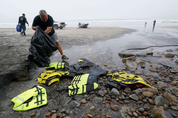 PHOTO: Boat salvager Robert Butler, front, picks up life preservers in front of one of two boats sitting on Blacks Beach, March 12, 2023, in San Diego. (Gregory Bull/AP)