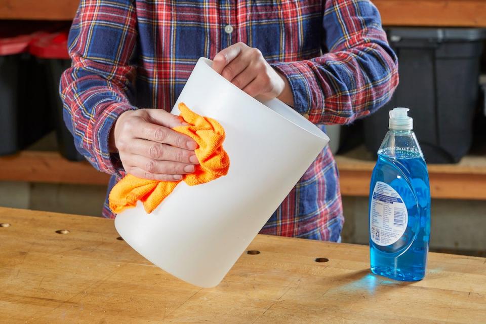 Woman using a microfiber cloth to clean a plastic bin.