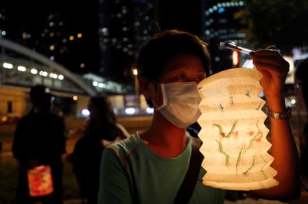 A protester wearing a mask holds a traditional lantern as people gather to form a human chain during the Mid-Autumn Festival at Lennon Wall at Admiralty district in Hong Kong