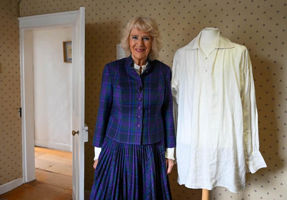 Queen Camilla next to the infamous shirt worn by Colin Firth in "Pride and Prejudice" on display at Jane Austen's House on April 6, 2022 in Alton, England.