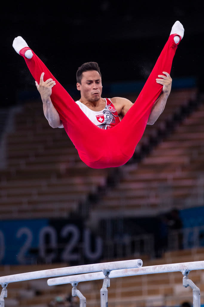 The gymnast is holding onto his legs in the v-position