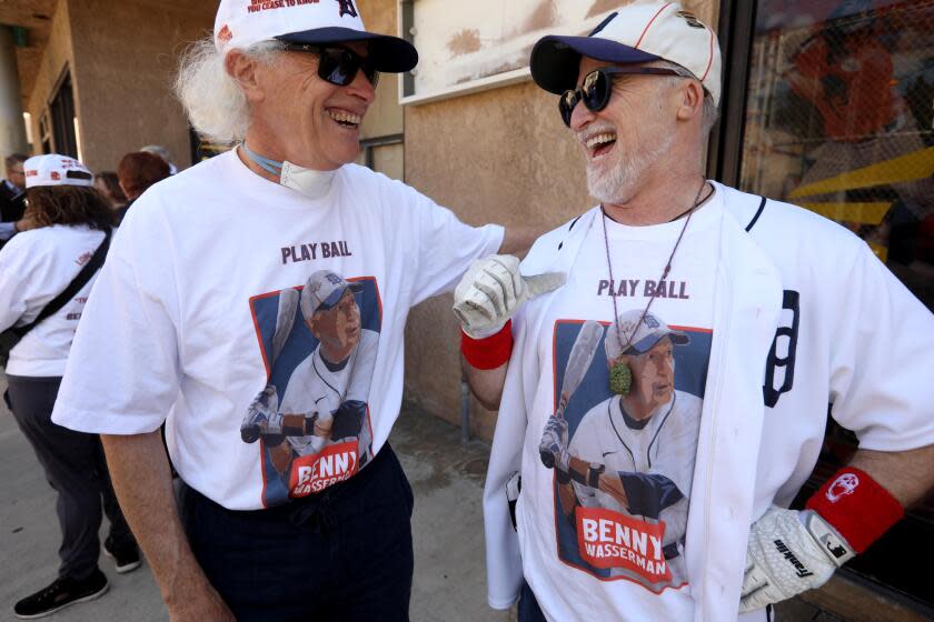 ANAHEIM, CA - APRIL 2, 2024 - - Michael Wasserman, left, and his brother Mark, enjoy a light moment at their father, Benny Wasserman's memorial, at Home Run Park Batting Cages in Anaheim on April 2, 2024. Wasserman was a weekly fixture at the batting cages and wanted to hit a 90 mph fastball when he turned 90. The memorial for Benny Wasserman was held on April 2, 2024, which would have been his 90th birthday, He passed away March 11, 2024. Wasserman worked in aerospace, as a technician and engineer. He was also an Albert Einstein impersonator appearing in commercials, movies and television. (Genaro Molina/Los Angeles Times)