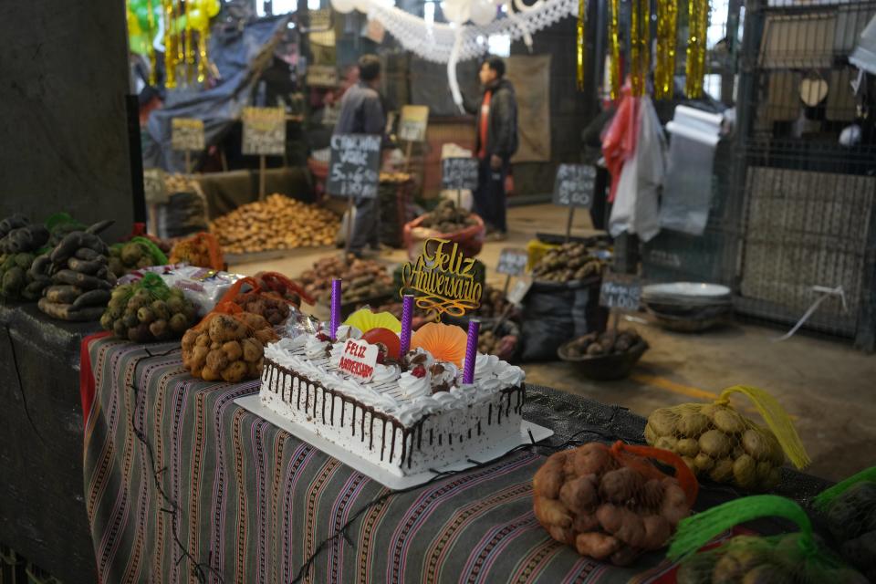 Un pastel de cumpleaños rodeado de diferentes tipo de papas para celebrar el Día Internacional de la Papa, en un mercado en Lima, Perú. Jueves 30 de mayo del 2024. (AP Foto/Martín Mejía)