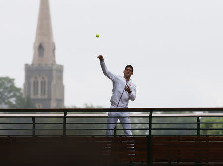 Novak Djokovic of Serbia throws balls at fans after he won his Men's Singles Final match against Roger Federer of Switzerland at the Wimbledon Tennis Championships in London, July 12, 2015. REUTERS/Stefan Wermuth