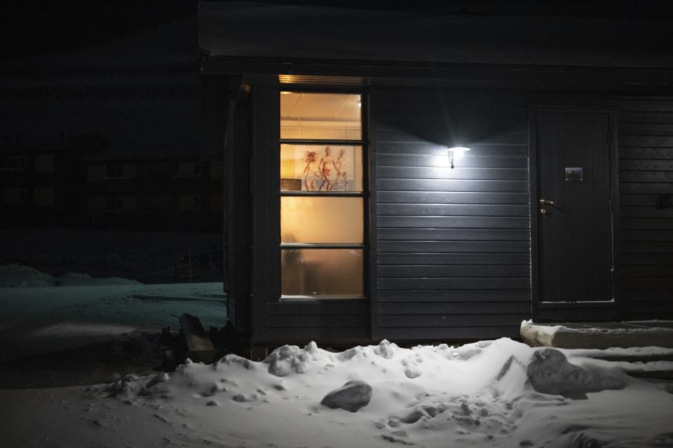 Un retrato de una familia corriendo en la playa está pegado en la ventana de una cabaña en Longyearbyen, Noruega, el jueves 11 de enero de 2023. (AP Foto/Daniel Cole)