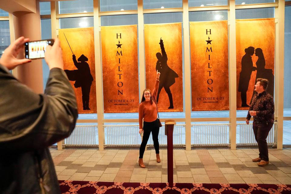 Eric Rutkowski watches as Emily Kurz poses in front of a "Hamilton" banner inside the Ohio Theatre during the show's opening night.