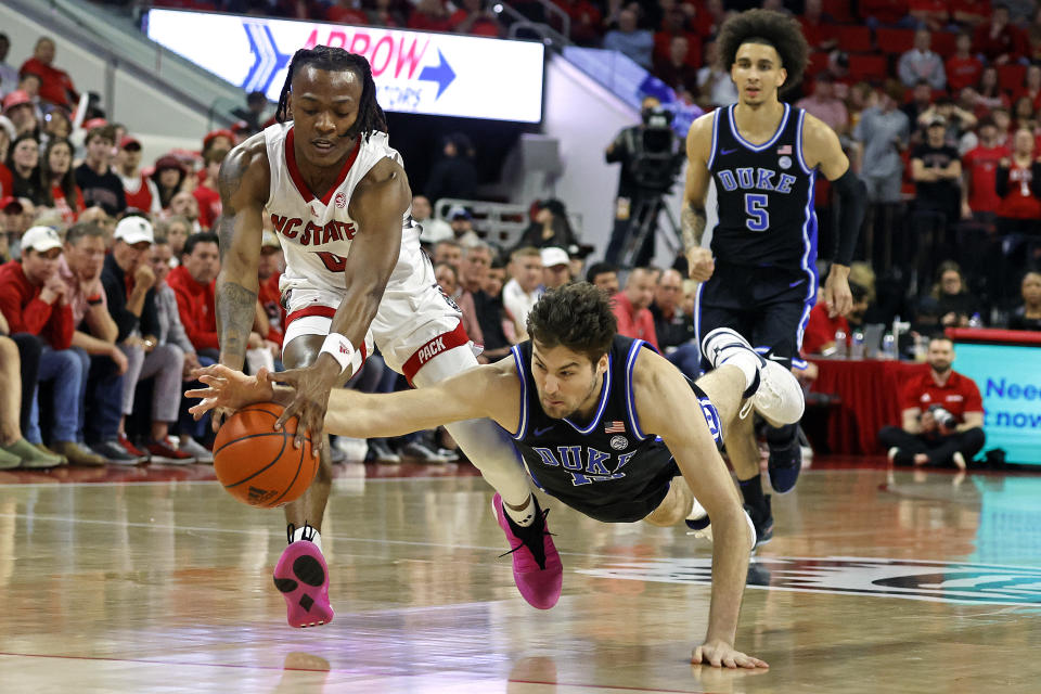 North Carolina State's DJ Horne, left, and Duke's Ryan Young, front right, dive for the ball during the first half of an NCAA college basketball game in Raleigh, N.C., Monday, March 4, 2024. (AP Photo/Karl B DeBlaker)