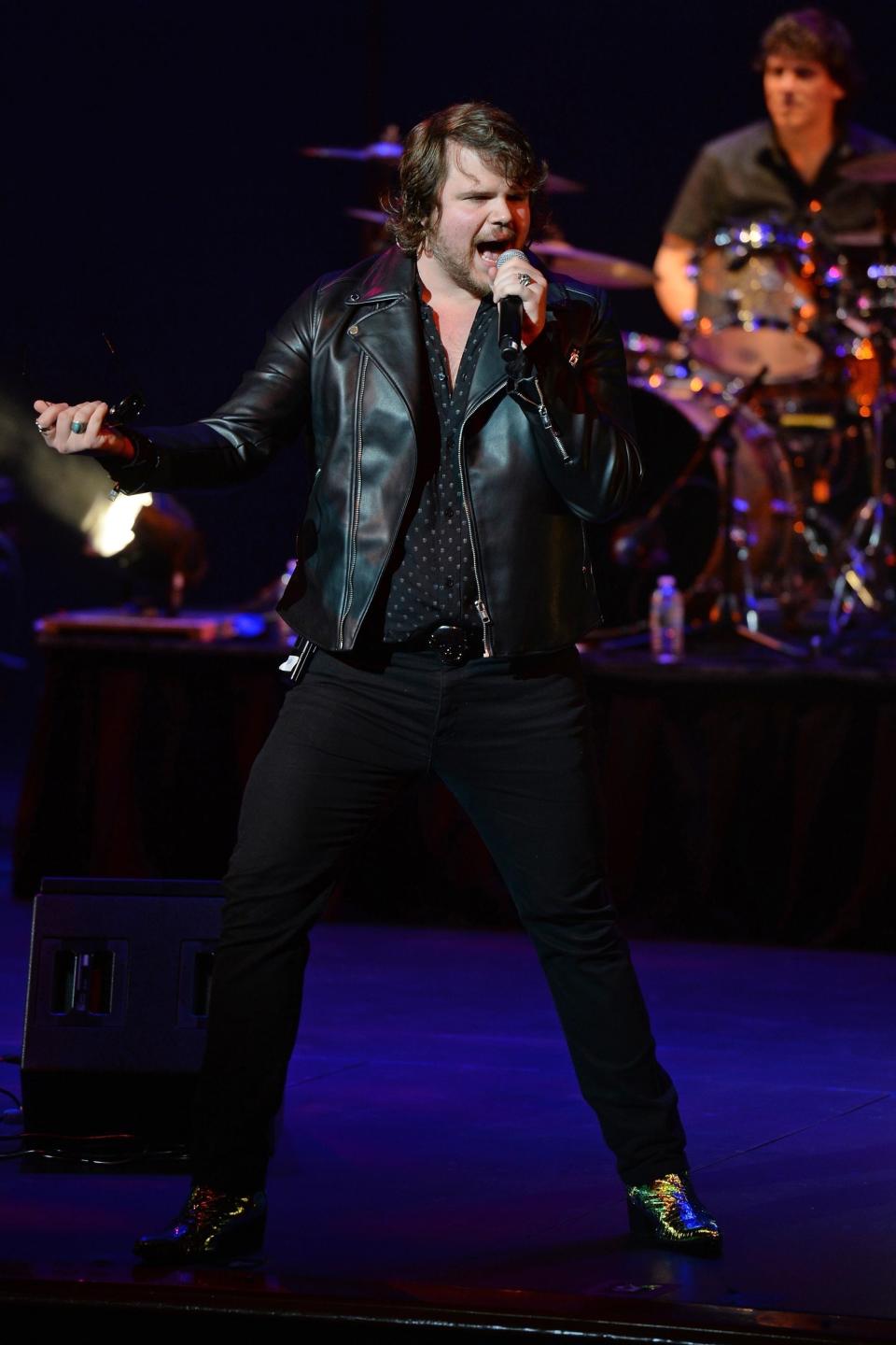 Caleb wearing a leather jacket while singing on stage