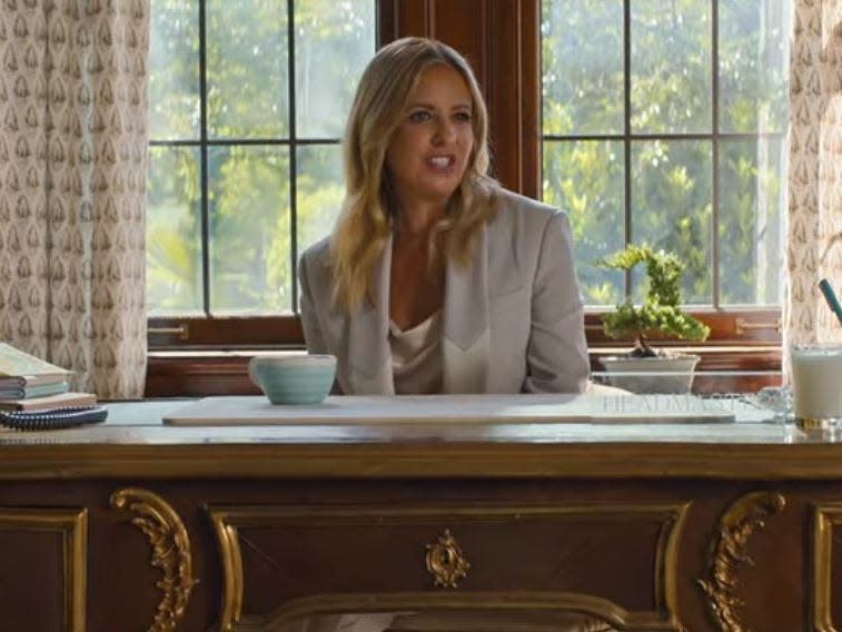 sarah michelle gellar as the school headmaster sitting behind her desk in do revenge