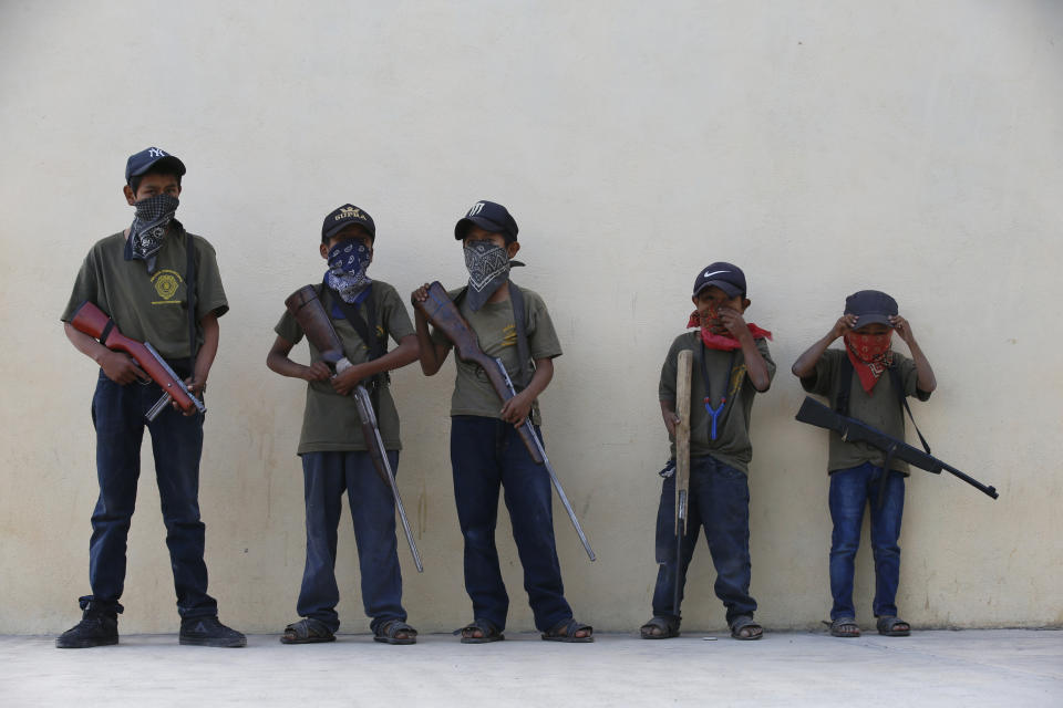 Children hold their training weapons, some real and some fake, during a display for the media designed to attract the federal government's attention to the dangers of organized crime their town negotiates daily in Ayahualtempa, Guerrero state, Mexico, Wednesday, April 28, 2021. International organizations have condemned the "recruitment" of children and warned of the effects. (AP Photo/Marco Ugarte)