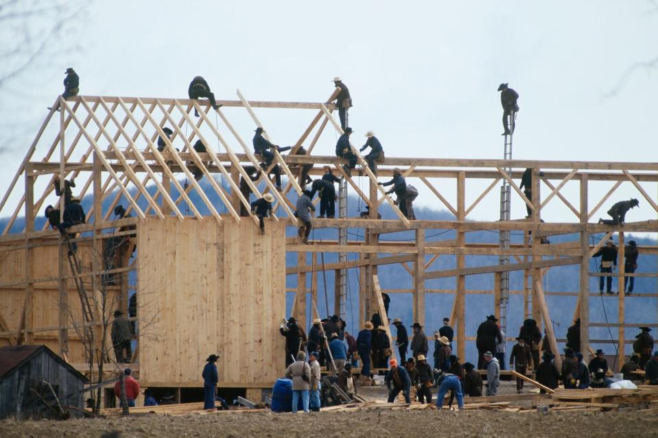 Amish men rebuild a barn destroyed by arson in 1992.