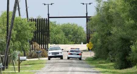 U.S. Border Patrol agents talk in their vehicles at the open gate in the 18-foot (five-metre) high rusty steel barrier along the U.S.- Mexico border near Fernando Rivera Jr.'s home in Brownsville, Texas September 2, 2014. REUTERS/Rick Wilking