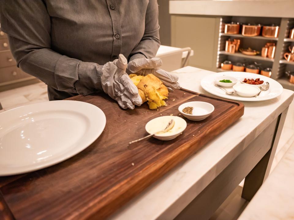 someone making baked potato at side of table