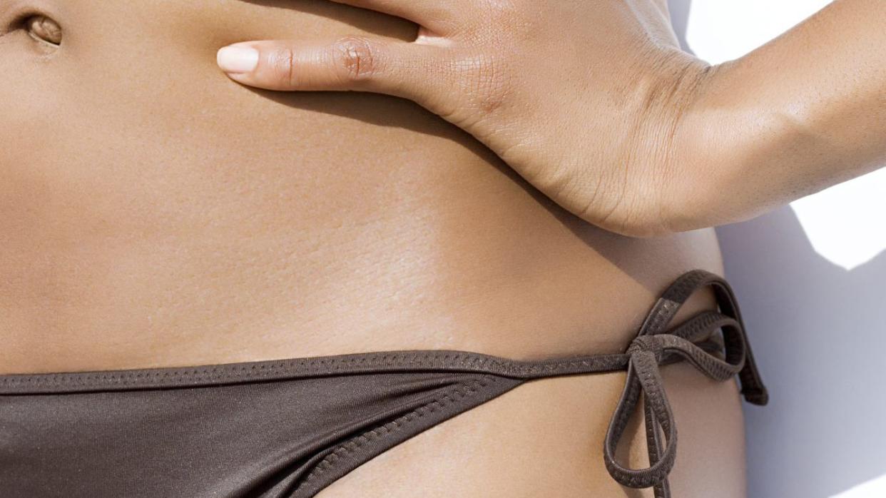 Close-up of the bottom half of a person's torso who is wearing a string bikini