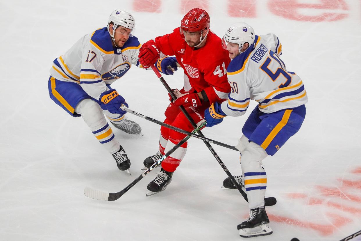 Detroit Red Wings defenseman Shayne Gostisbehere (41) is defended by Buffalo Sabres center Tyson Jost (17) and left wing Eric Robinson (50) during the first period at Little Caesars Arena in Detroit on Sunday, April 7, 2024.