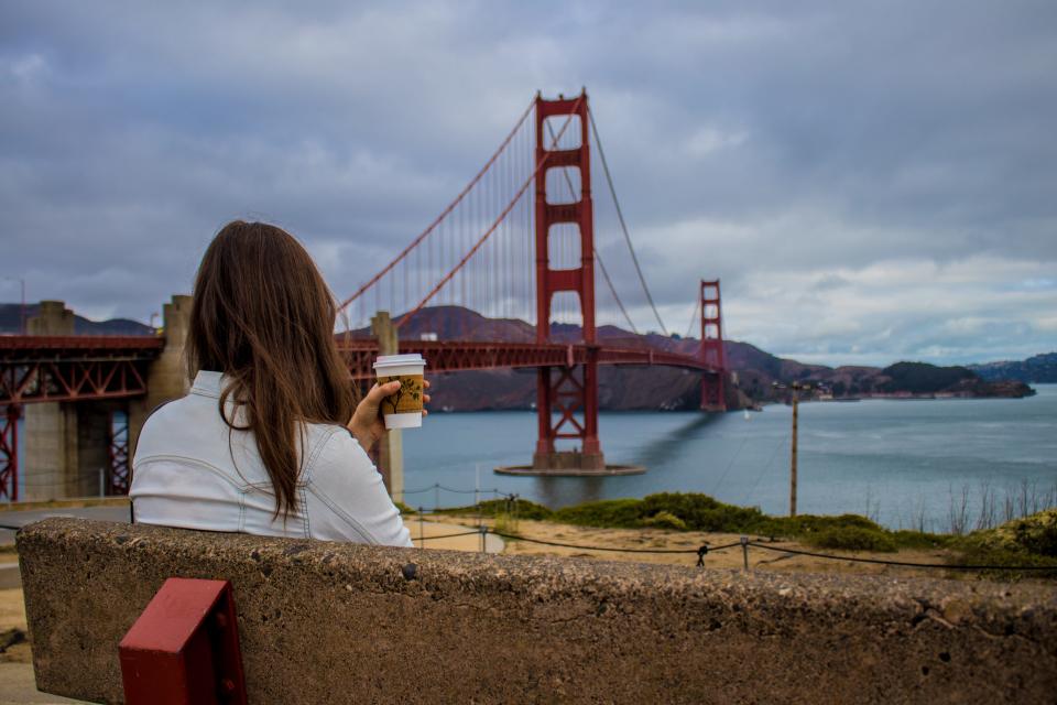 Woman drinking coffee by the Golden Gate bridge
