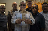 Evangelical Pastor Moisés de Prada poses with members of his church as he holds a cross made out of the words to the prayer "Our Father" in Havana, Cuba, Tuesday, Oct. 12, 2021. The idea of same-sex marriage bothers De Prada, who like many of his parishioners opposes a proposal to legalize it in Cuba, where Pentecostal churches have been growing. (AP Photo/Ramon Espinosa)