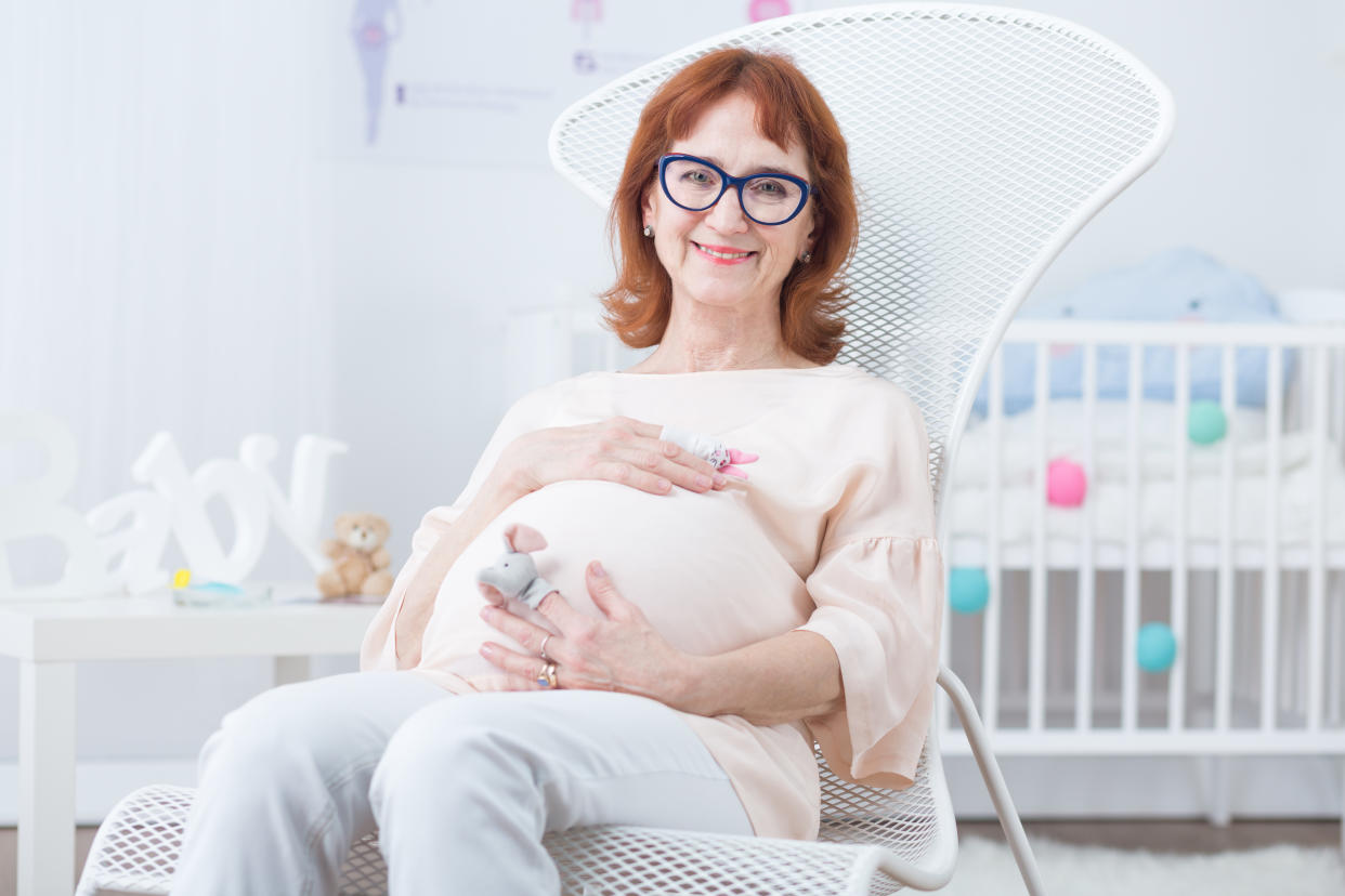 Older happy woman in pregnant resting on armchair