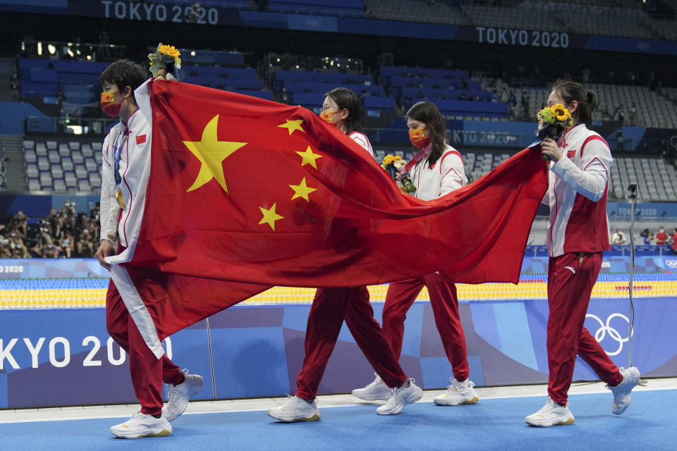 China's women's 4x200-meter freestyle relay team, of Yang Junxuan, Tang Muhan, Zhang Yifan and Li Bingjie carry their national flag after receiving their gold medals at the 2020 Summer Olympics, Thursday, July 29, 2021, in Tokyo, Japan. (AP Photo/Matthias Schrader)