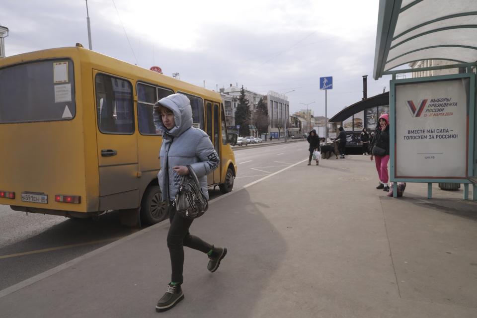 A woman walks past a billboard which promote the upcoming presidential election with words in Russian: "Together we are strong, we vote for Russia!" on a bus stop in Luhansk, the capital of Russian-controlled Luhansk region, eastern Ukraine, on Thursday, March 14, 2024. Russian President Vladimir Putin Thursday called on people in Ukraine's occupied regions to vote, telling them and Russians that participation in the elections is "manifestation of patriotic feeling," Presidential elections are scheduled in Russia for March 17. (AP Photo)