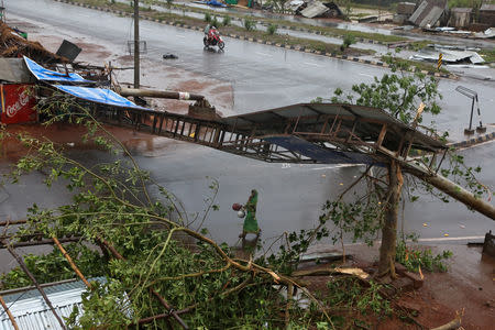 A woman carries pitchers next to uprooted trees and a fallen signboard following Cyclone Fani in Khordha district in the eastern state of Odisha, India, May 3, 2019. REUTERS/R Narendra