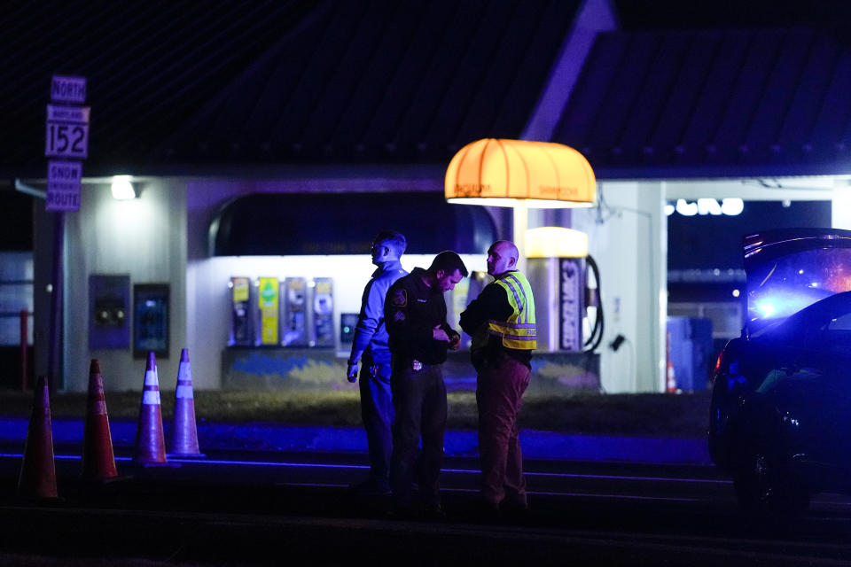 Police officers stand at a checkpoint on Mountain Road and Belair Road where a suspected gunman is believed to be at large, Thursday, Feb. 9, 2023, in Fallston, Md. A second police officer in Maryland has been injured in gunfire as Baltimore County police continue searching for a suspect amid a large manhunt that began after a different officer was shot Wednesday. (AP Photo/Julio Cortez)