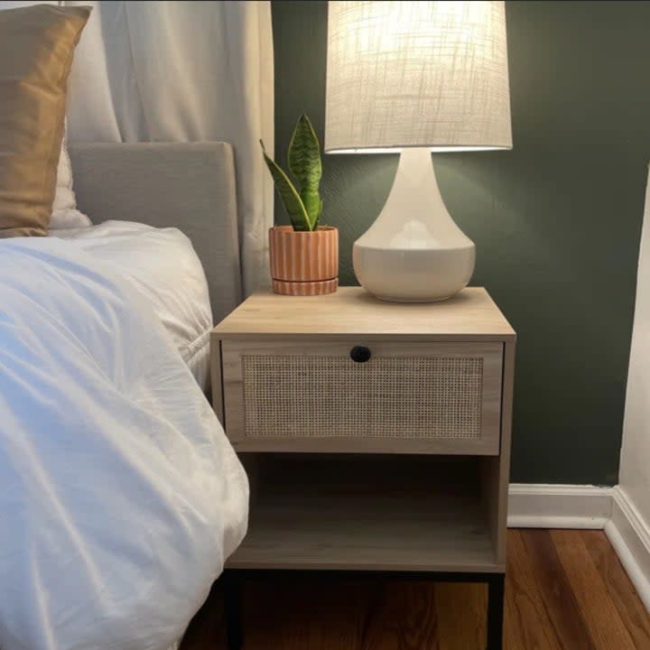 A beige nightstand with a lamp on top