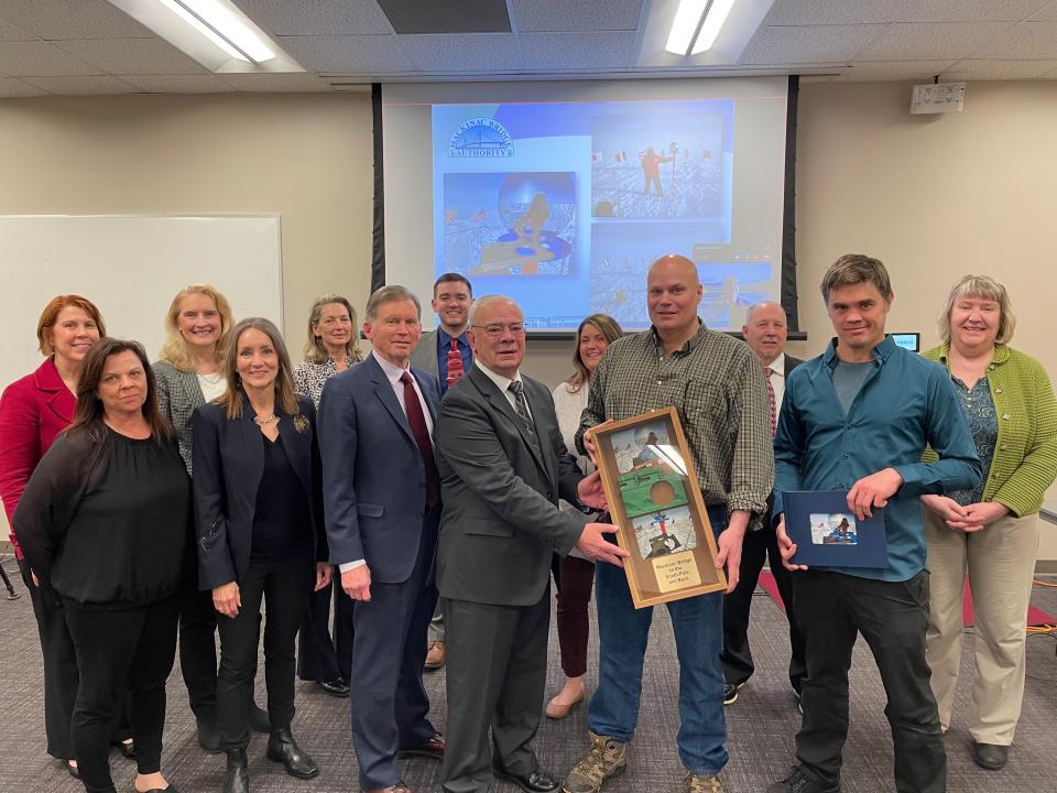 Brendan Fisher presents a shadowbox with photos and a piece of Mackinac Bridge steel used to make the current ceremonial and geographical South Pole markers to the Mackinac Bridge Authority.