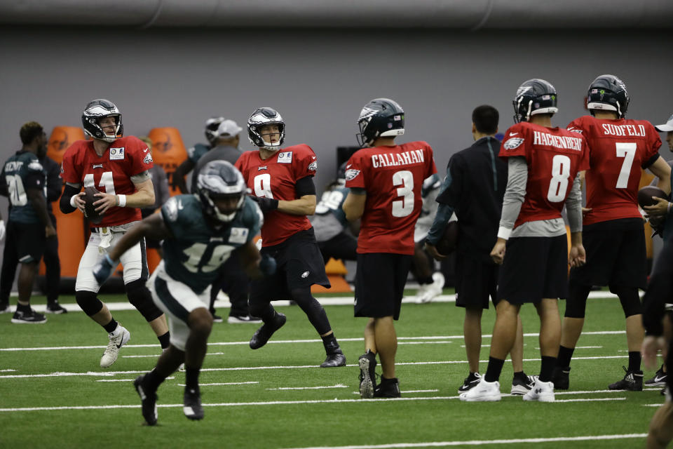 Philadelphia Eagles quarterbacks Carson Wentz (11) and Nick Foles (9) throw passes as Joe Callahan (3), Christian Hackenberg (8) and Nate Sudfeld (7) look on during NFL football training camp in Philadelphia, Monday, Aug. 13, 2018. (AP Photo/Matt Rourke)